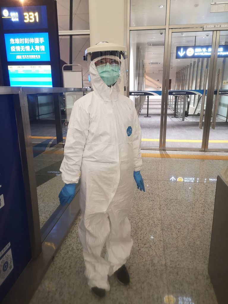 參與第二批武漢包機的護理師賴碧蓮27日坦言,居家檢疫第6天確實有點孤獨焦慮,她雖無法出門,但可將頭、手伸窗外曬太陽舒壓。圖為賴碧蓮穿著全套防護裝協助武漢包機旅客返台。(賴碧蓮提供)