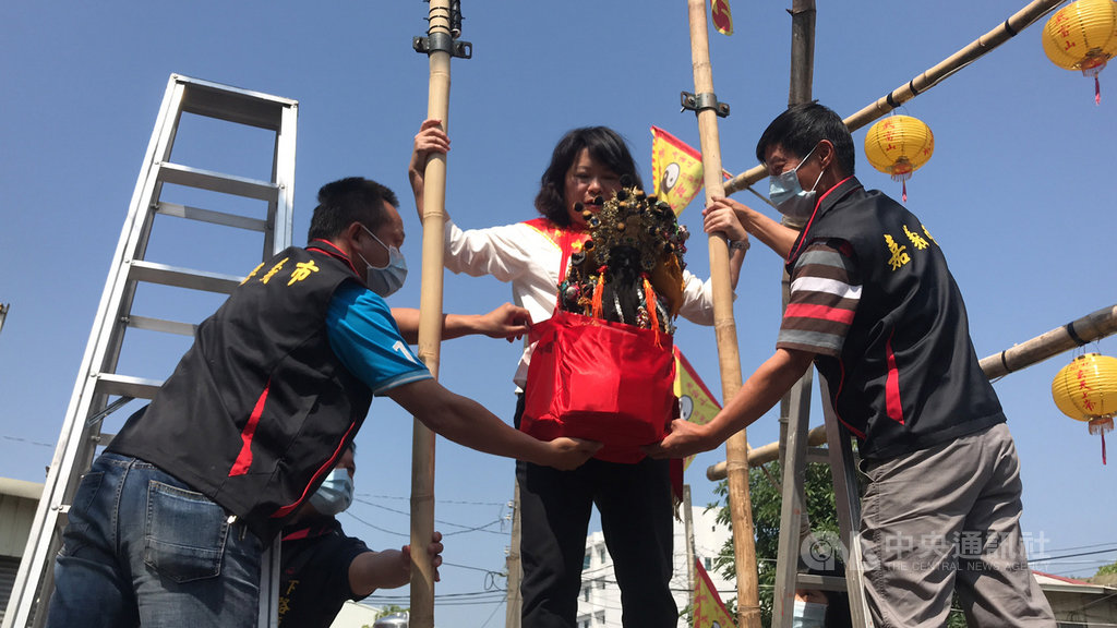 嘉義市下路頭武當山玄天上帝廟29日為神明祝壽,嘉義市長黃敏惠(中)揹神像爬上鞦韆架,發送錢母給信眾保平安。中央社記者姜宜菁攝 109年3月29日