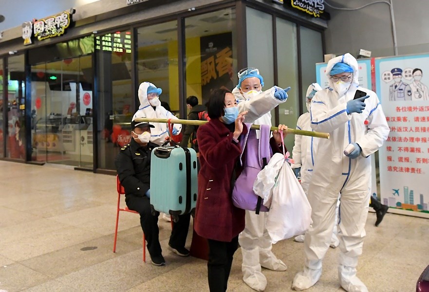 中國武漢肺炎28日共新增確診45例,其中1例為來自河南的本土病例。圖為武漢市火車站28日重啟後旅客自廣州南站出發列車抵達,做足全身防護的工作人員指引方向。(中新社提供)