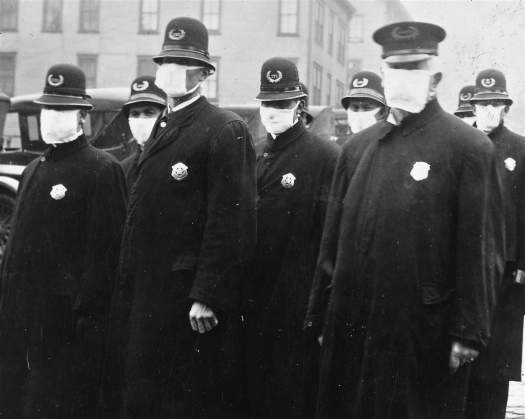 1918年爆發的全球流感疫情,當年造成5億人感染、數千萬人死亡,回顧美國當時的每一張照片,最顯著的特徵是每個人都戴著口罩。圖為1918年12月西雅圖警察戴口罩抗疫。(圖取自維基百科,版權屬公有領域)