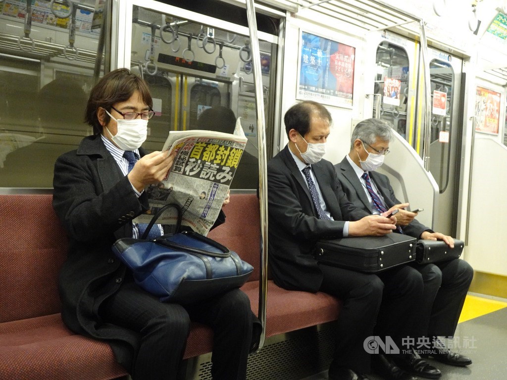 武漢肺炎疫情擴散,東京民眾憂封城,搭乘地鐵民眾閱讀頭版為「封城進入秒讀」的報紙。中央社記者楊明珠東京攝 109年3月26日