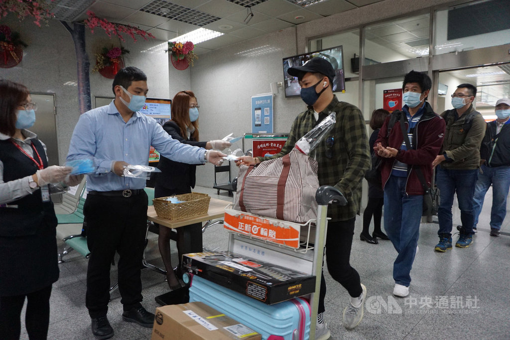 為了讓返鄉民眾或來金門旅客多一層保護,在地業者總經理特助葉杭(左2)等人2日帶領員工在尚義機場入境大廳迎接旅客,先以酒精為他們消毒,再分贈每人一枚口罩。中央社記者黃慧敏攝 109年4月2日