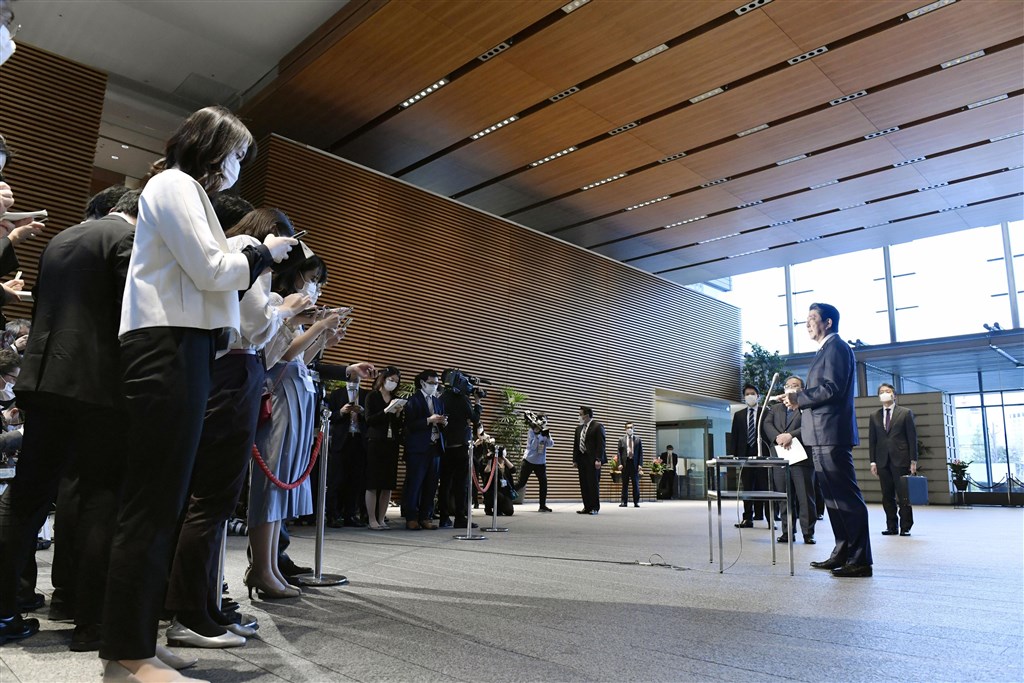 日本首相安倍晉三(右)6日表示,快則7日將發布「緊急事態宣言」。圖為記者會現場安倍與記者團採取保持距離措施。(共同社提供)
