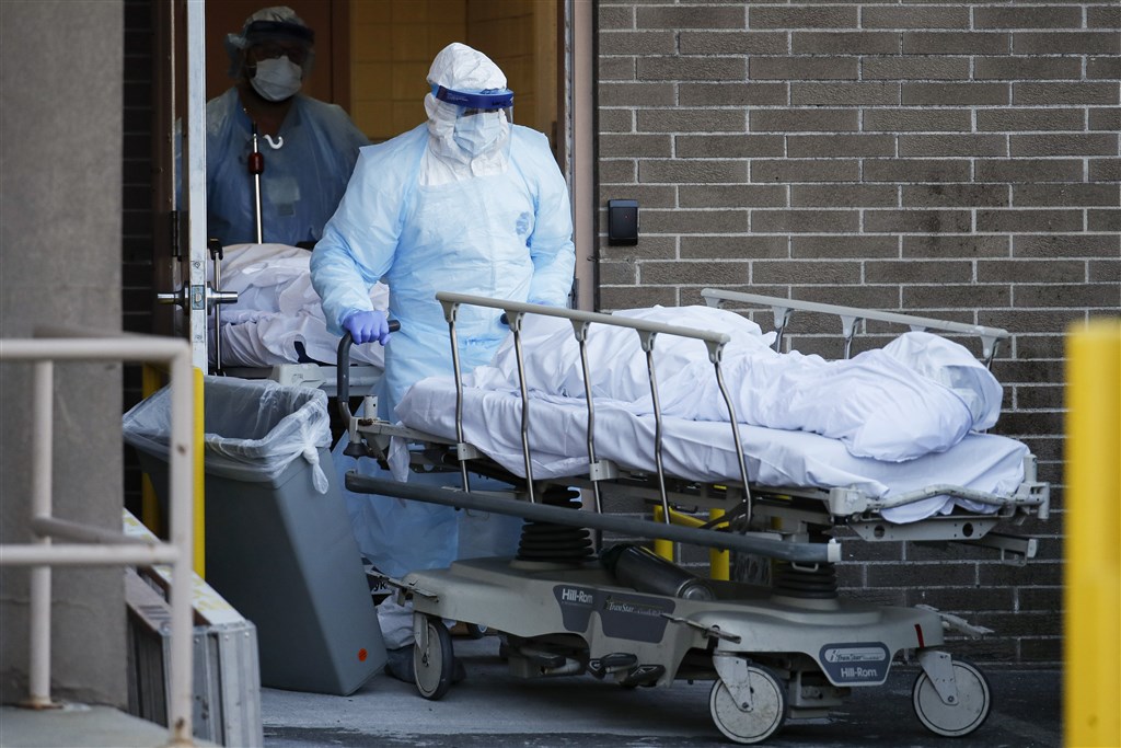 截至6日,紐約武漢肺炎的死亡病例攀升至3485起。在此之際,穿著防護衣的醫護人員運送擔架上蓋著白布的遺體,成為各家醫院外頭常見的景象。(美聯社)