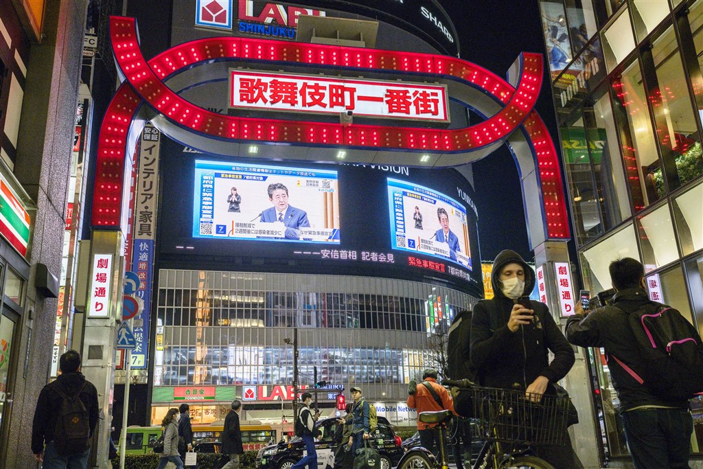 日本首相安倍晉三7日宣布對東京等7地發布緊急事態宣言,東京新宿街頭民眾觀看大螢幕上記者會播放畫面。(共同社提供)
