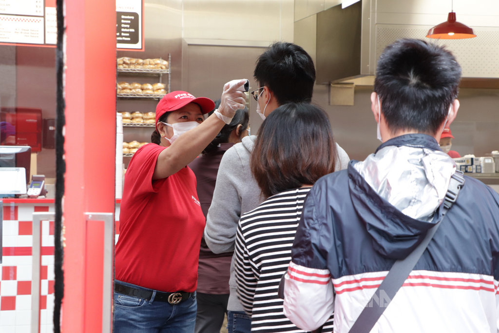 港府決定補貼員工薪酬,以保障市民在疫情衝擊下不會失業,市場對此反應正面,相關公司股價紛紛9日紛紛上漲;圖為一家餐飲店的員工為客人量度體溫。中央社記者張謙香港攝 109年4月9日