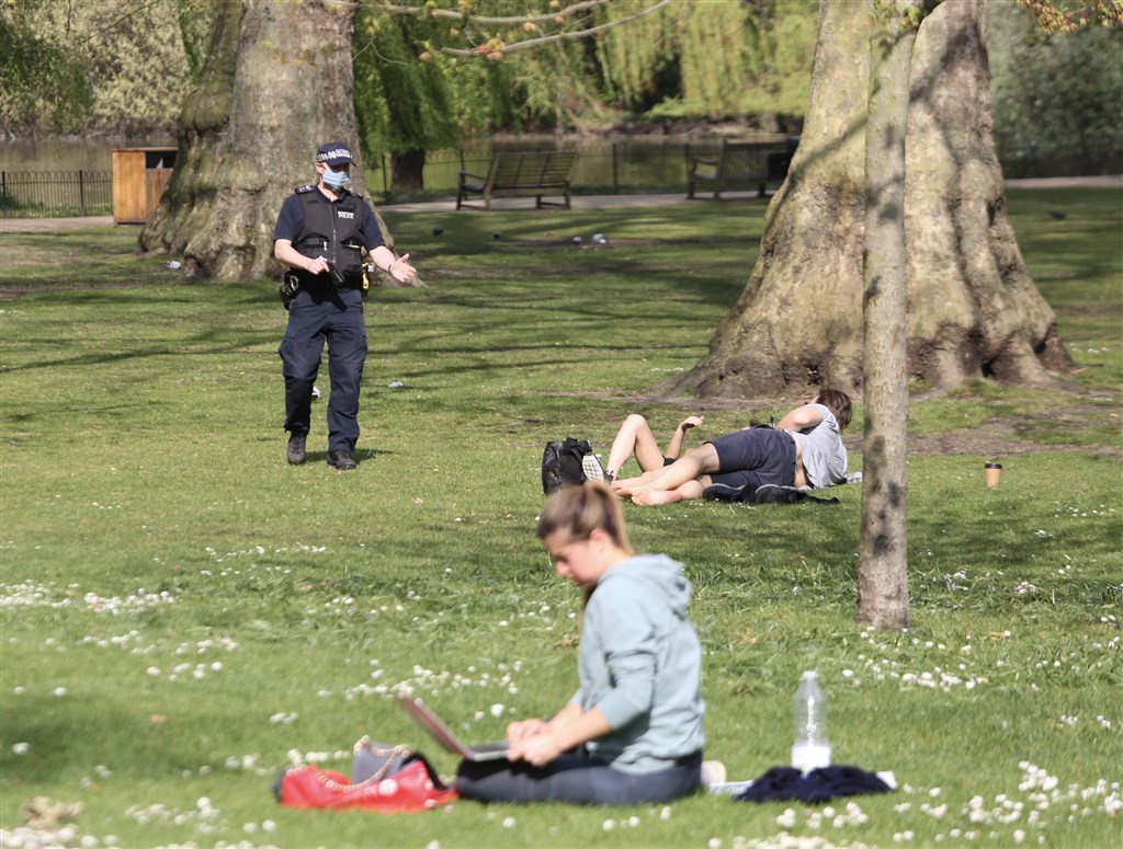 英國倫敦民眾不聽政府勸告，在公園享受日光浴時未保持社交安全距離，遭到警方前來警告。（安納杜魯新聞社提供）