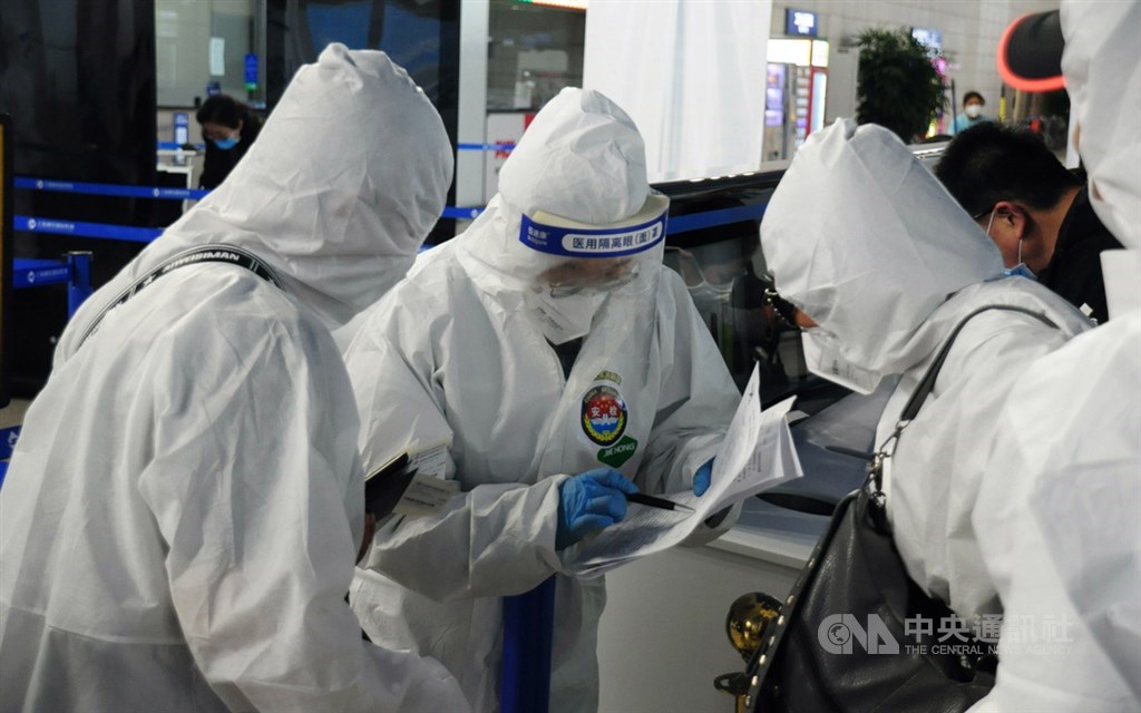 兩名搭乘20日晚間類包機的國人穿上自備的防護衣,和上海機場防疫人員(中)核對資料。中央社記者沈朋達上海攝 109年4月20日
