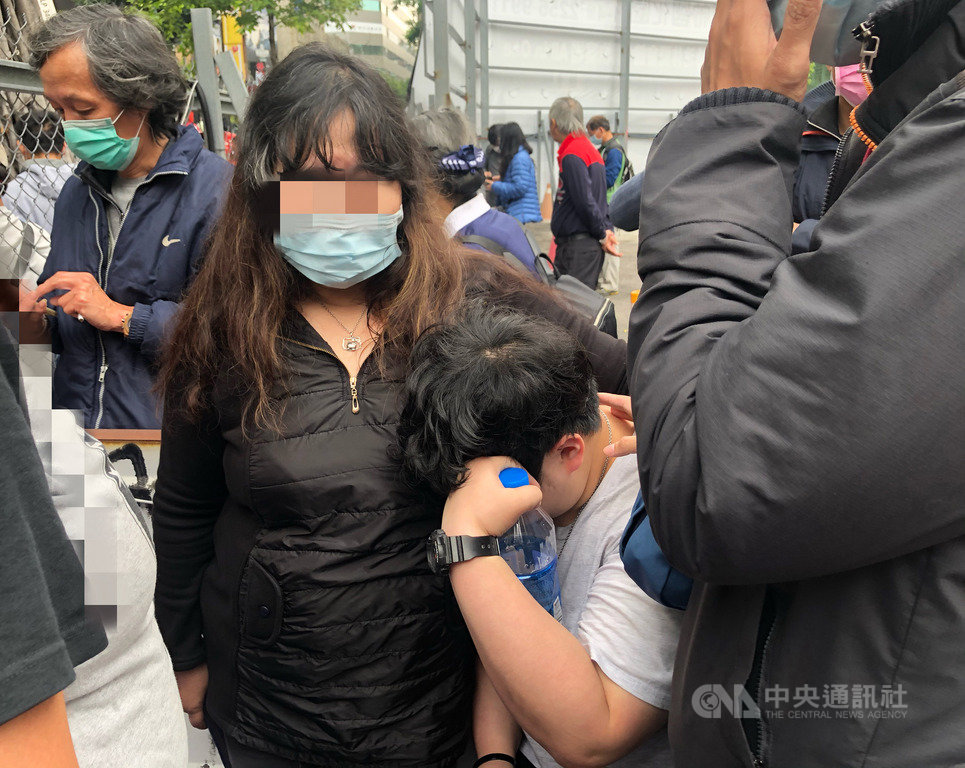 台北市林森北路錢櫃26日上午驚傳火警,至下午已釀5死2命危及多人受傷。一名母親(前左)事發後焦急趕到現場尋找在錢櫃打工的女兒(右2白衣者),所幸最後女兒平安獲救,兩人難掩激動、相擁而泣。中央社記者林長順攝 109年4月26日