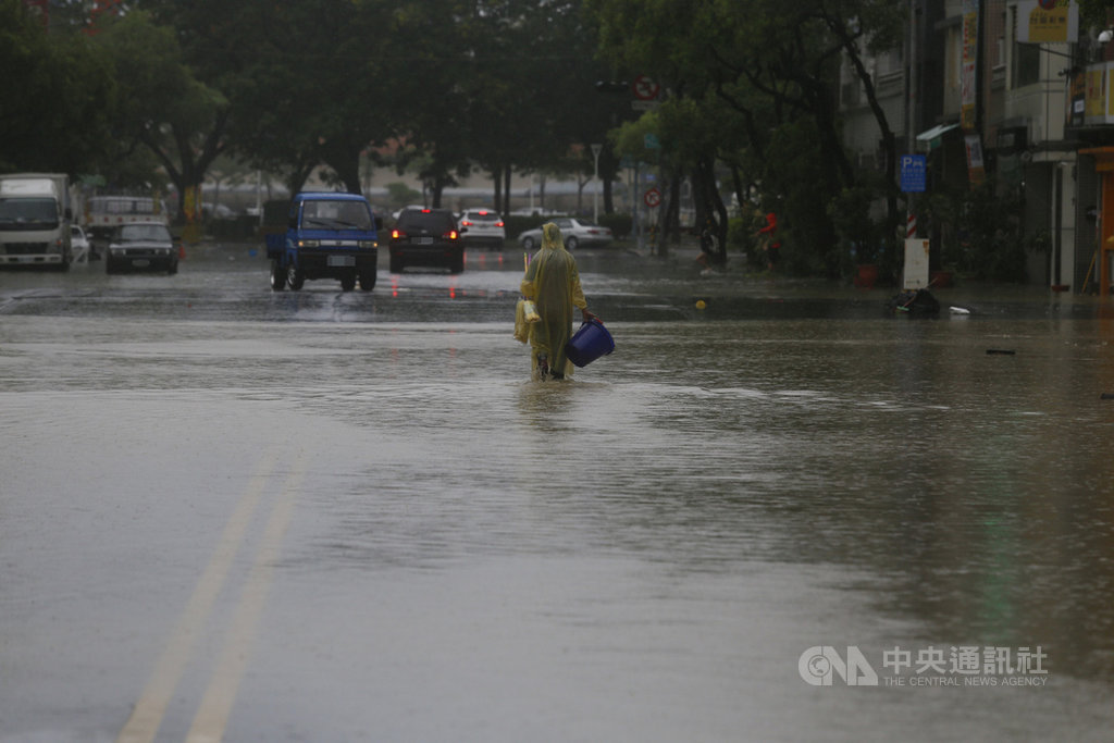 受滯留鋒面及西南氣流影響,高雄市區22日下起滂沱大雨,鹽埕區七賢抽水站有一台抽水機故障,造成大公路、富野路一帶無法排水,民眾拿著水桶在雨中前行。中央社記者董俊志攝 109年5月22日