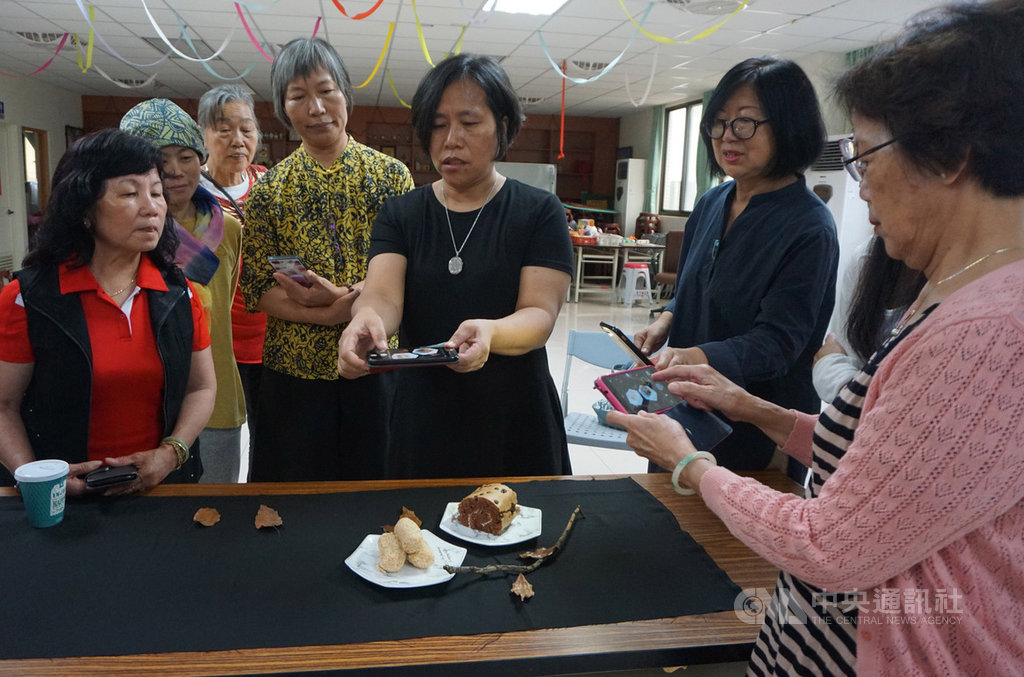金門縣古寧頭社區發展協會22日邀請手機攝影達人周麗紅(右3)授課,指導學員靜物拍攝技巧,周麗紅說,只拍一個蛋糕顯得單調,她隨手擺上幾片枯葉,再放上枯枝,整個畫面立時豐富不少。中央社記者黃慧敏攝 109年5月22日