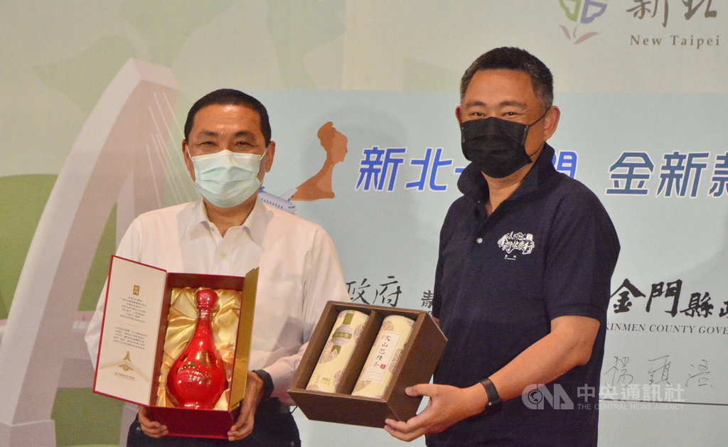 新北市長侯友宜(左)與金門縣長楊鎮浯(右)攜手帶動旅遊商機,共同規劃互惠旅遊,將啟動觀光業者包機踩線團,22日在新北市舉行記者會,兩人互贈金門高粱酒與文山包種茶。中央社記者黃旭昇新北攝 109年5月22日