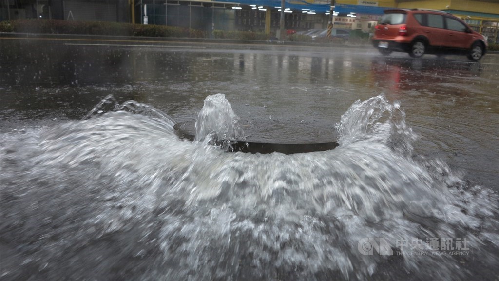 受滯留鋒面影響,高雄市22日一早滂沱大雨,造成部分路段積水,因排水不及,人孔蓋噴出水柱。中央社記者董俊志攝 109年5月22日