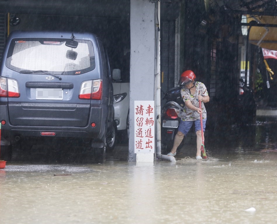 高雄市22日滂沱大雨,鹽埕區七賢三路一帶道路出現積水情形,民眾趁雨勢漸歇,加緊腳步在自家門口掃除積水。中央社記者董俊志攝 109年5月22日