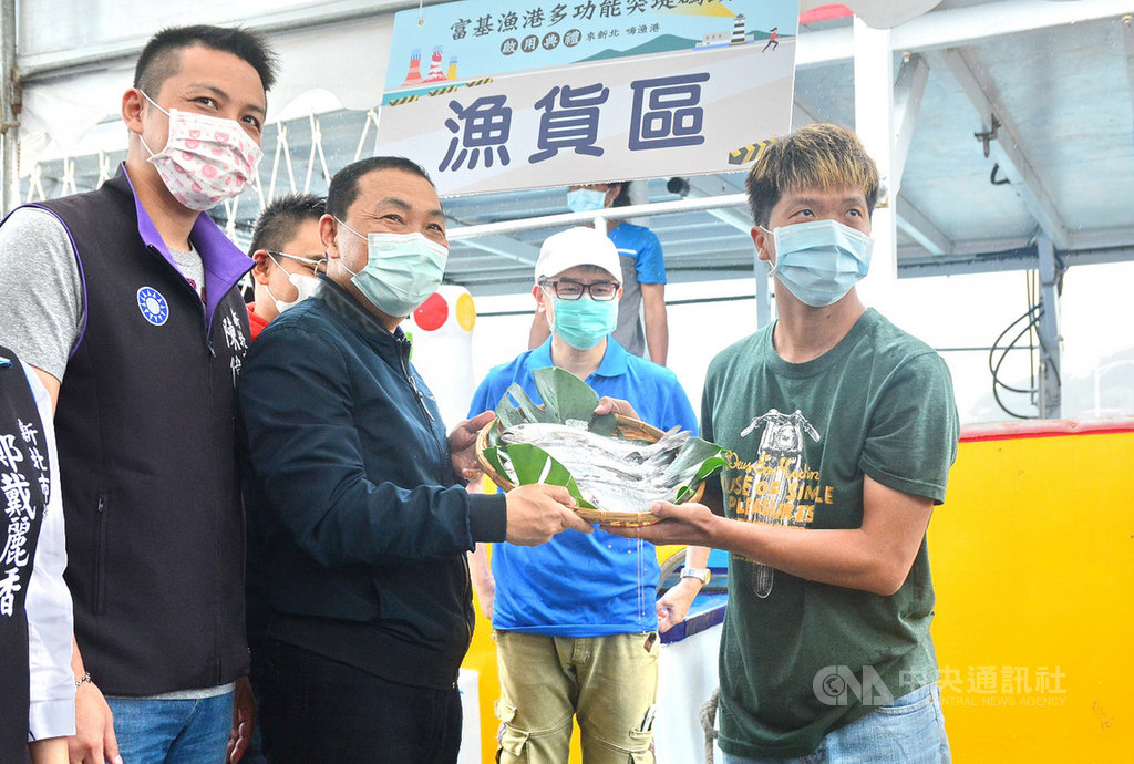 新北市富基漁港多功能突堤碼頭23日啟用,漁船船位、碼頭的作業空間更大,大風浪時可停泊更多船隻,市長侯友宜(前左2)前往視察時,有船長送上新鮮漁獲。(新北市漁業處提供)中央社記者黃旭昇新北傳真 109年5月23日