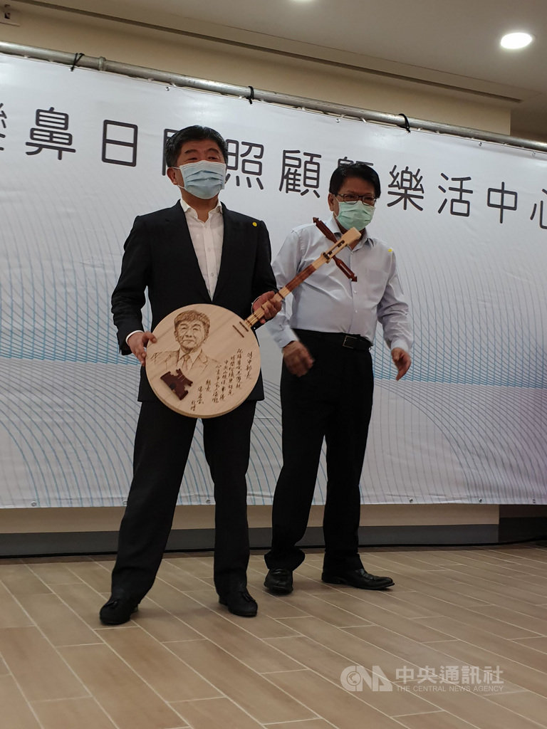 中央流行疫情指揮中心率團到屏東示範兩天一夜樂活旅遊,24日首站行程是台灣最南端的鵝鑾鼻日間照顧中心,屏東縣長潘孟安(右)贈送指揮官陳時中(左)一把畫有他肖像的月琴。中央社記者陳偉婷攝 109年5月24日