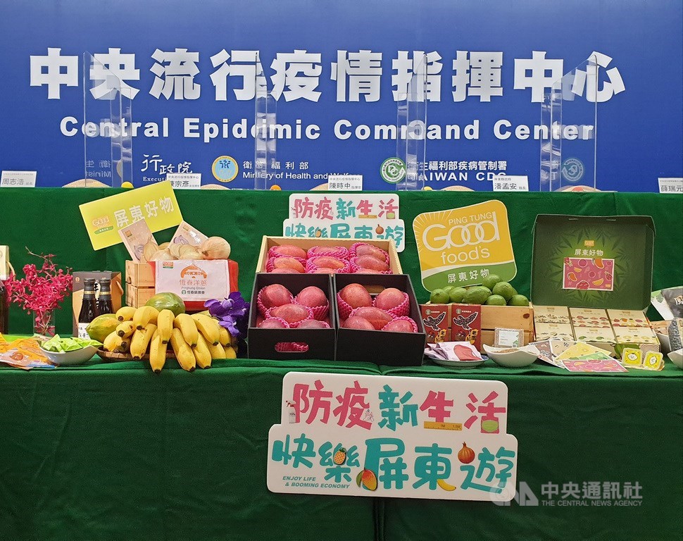 中央疫情指揮中心23日到屏東墾丁示範兩天一夜樂活防疫旅行,疫情記者會也首度移師屏東。屏東縣政府在現場複製台北疫情指揮中模式,除背板一致、有透明隔板,現場也擺出超過10款屏東農產和好物。中央社記者陳偉婷攝 109年5月24日