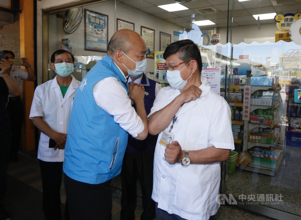 高雄市長韓國瑜(前左)1日頒發感謝狀給人禾藥局負責人藥師湯金獅(前右),感謝業者配合實名制販售近10萬份口罩的辛勞。兩人見面時,先屈肘互碰代替握手打招呼。中央社記者董俊志攝 109年6月1日