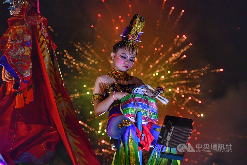 台東大甲鎮瀾宮媽祖11日深夜11時將起駕,鎮瀾宮廟埕越夜越熱鬧,煙火不時迸裂,各式藝陣花車齊聚,等待媽祖起駕時刻到來,一名演出者晚間把握空檔休息。中央社記者王飛華攝 109年6月11日