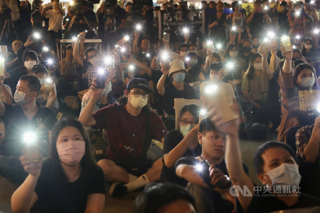 「抗爭未完，台港同行」反送中週年晚會13日在台北自由廣場登場，與會民眾席地而坐，隨著舞台演出，拿出手機點亮燈光，盼為港人點亮希望。中央社記者張皓安攝　109年6月13日