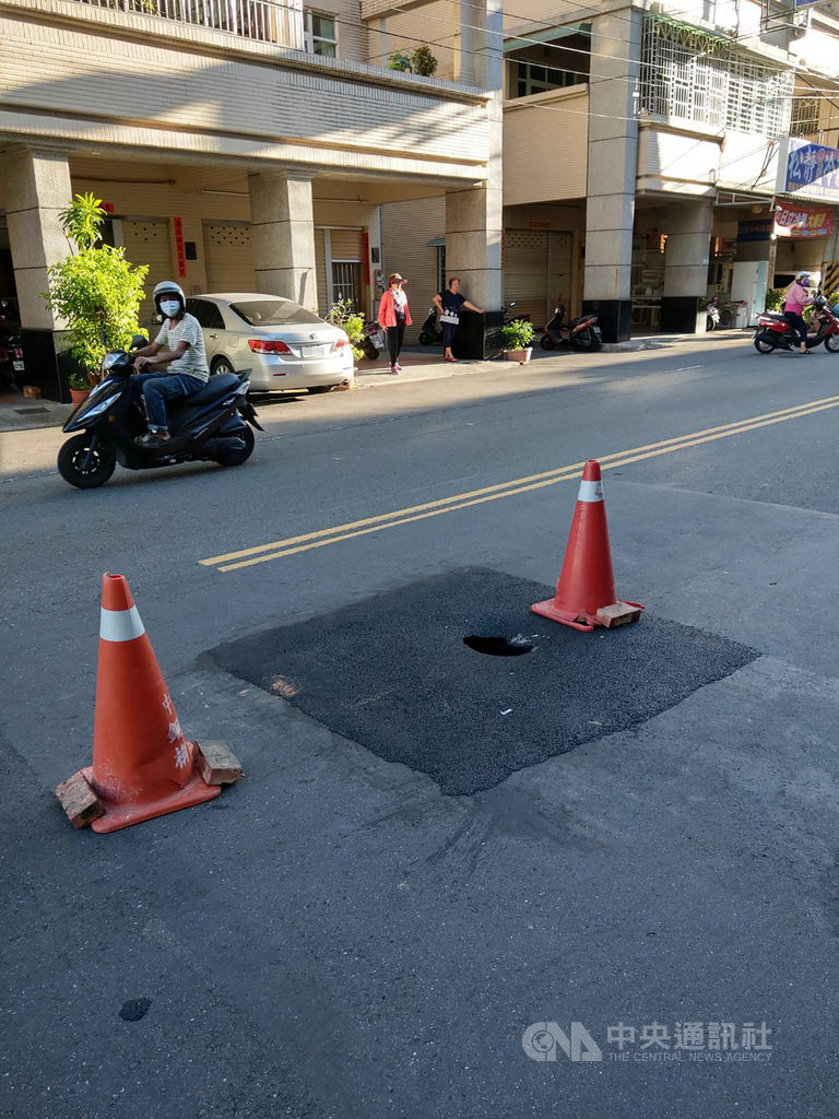 高雄市鳳山區力行路道路下陷,養工處10日修補完成,11日又下陷並出現坑洞,導致一名機車騎士15日下午摔傷,工程單位於是架設三角錐做警示。(鳳山區鎮北里長提供)中央社記者王淑芬傳真 109年6月15日