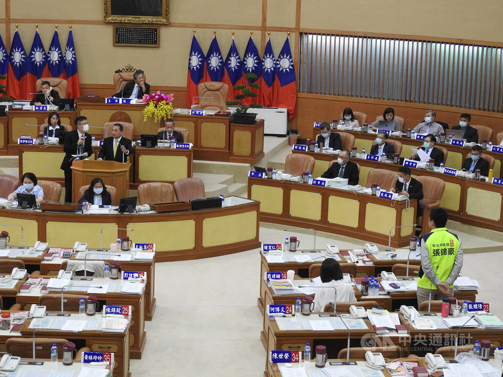 新北市議會29日進行市政總質詢,民進黨議員張錦豪(右立者)指出,近來天氣炎熱,國中小學童水壺一下子就見底,學校飲水機的溫冰水溫實測超燙,盼市府解決學童飲水問題。中央社記者王鴻國攝 109年6月29日