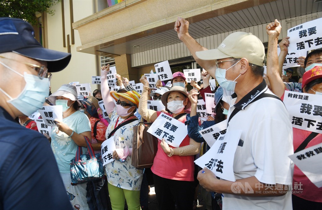 台北市政府規劃改建雙連段帶狀公園,引發居民與攤商抗議。北捷30日表示,原訂7月1日架設施工圍籬延至7月15日。圖為雙連市集攤商舉看板呼口號,抗議帶狀公園改建沒有配套措施讓他們無路可走。(中央社檔案照片)