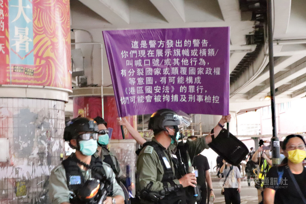 「港區國安法」生效,港警1日面對自行上街「七一」遊行的群眾,首度舉出了象徵執行此法的紫色旗幟。中央社記者張謙香港攝 109年7月1日