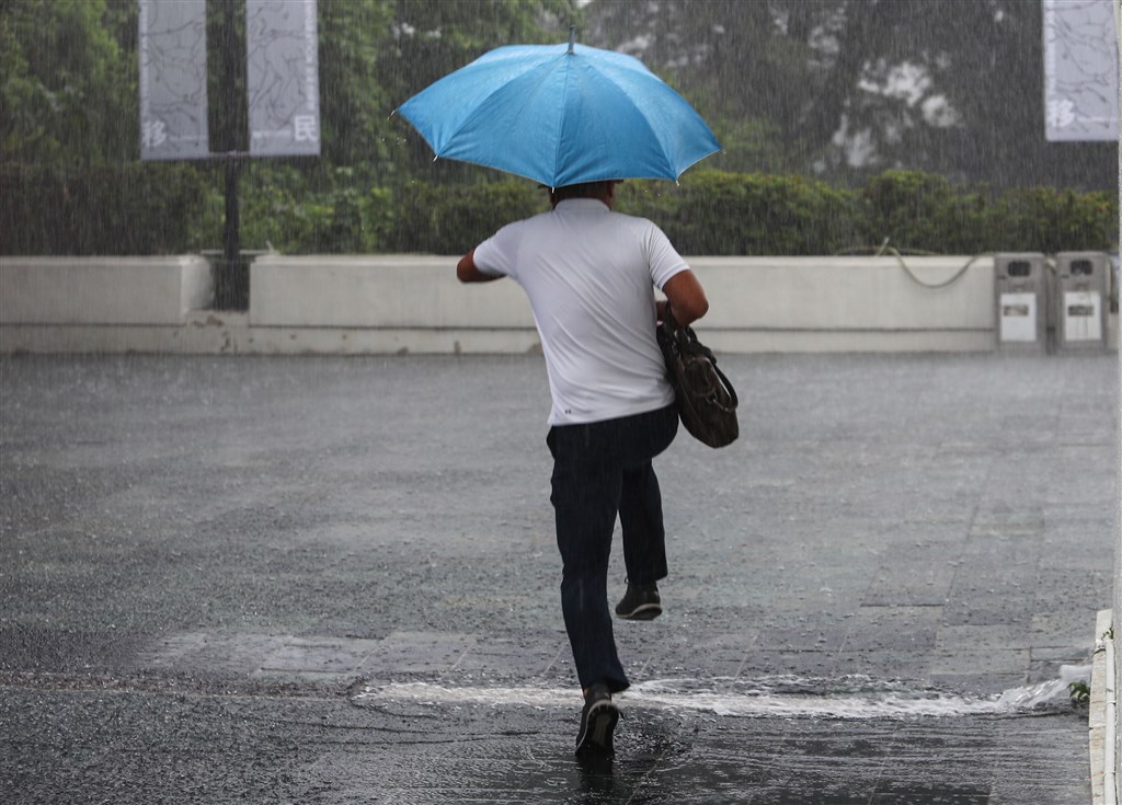 對流雲系發展旺盛,台北2日午後降下大雷雨,滂沱大雨造成路面積水,外出民眾高高跳起閃過積水處。 中央社記者王騰毅攝 109年7月2日