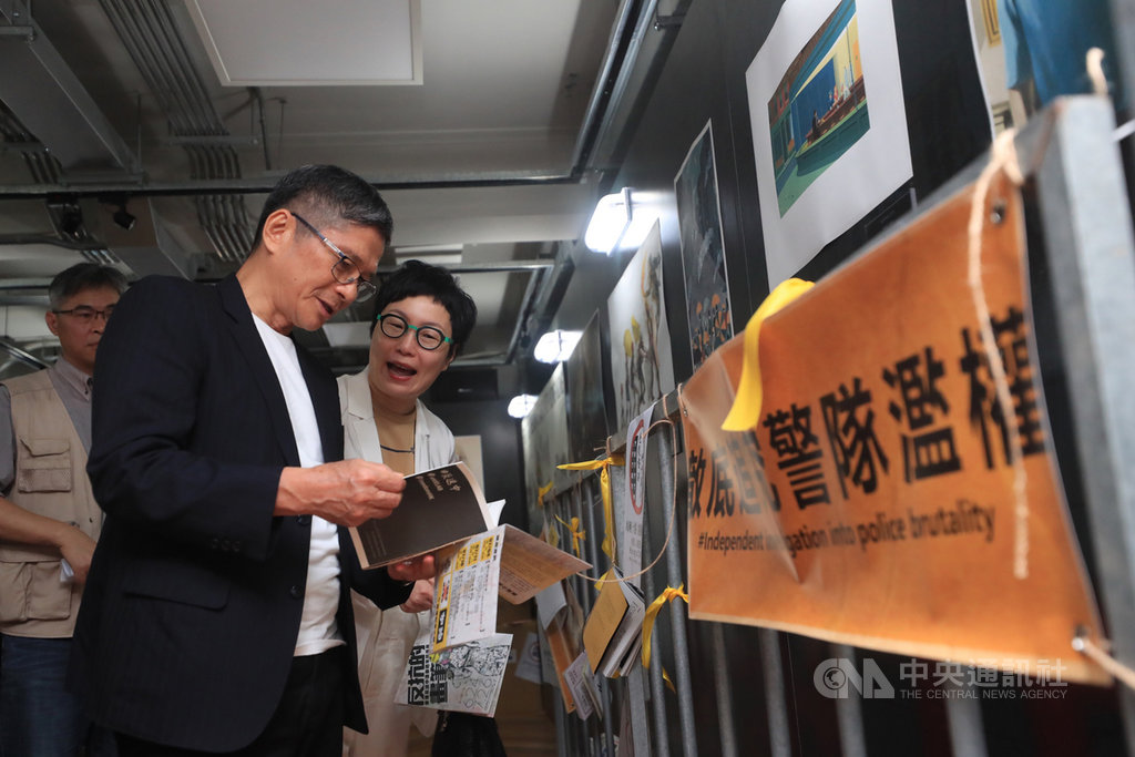 文化部長李永得(前左)4日在台灣漫畫基地參觀「反抗的畫筆-香港反送中運動週年圖像展」,觀看展區相關手冊。中央社記者吳家昇攝 109年7月4日
