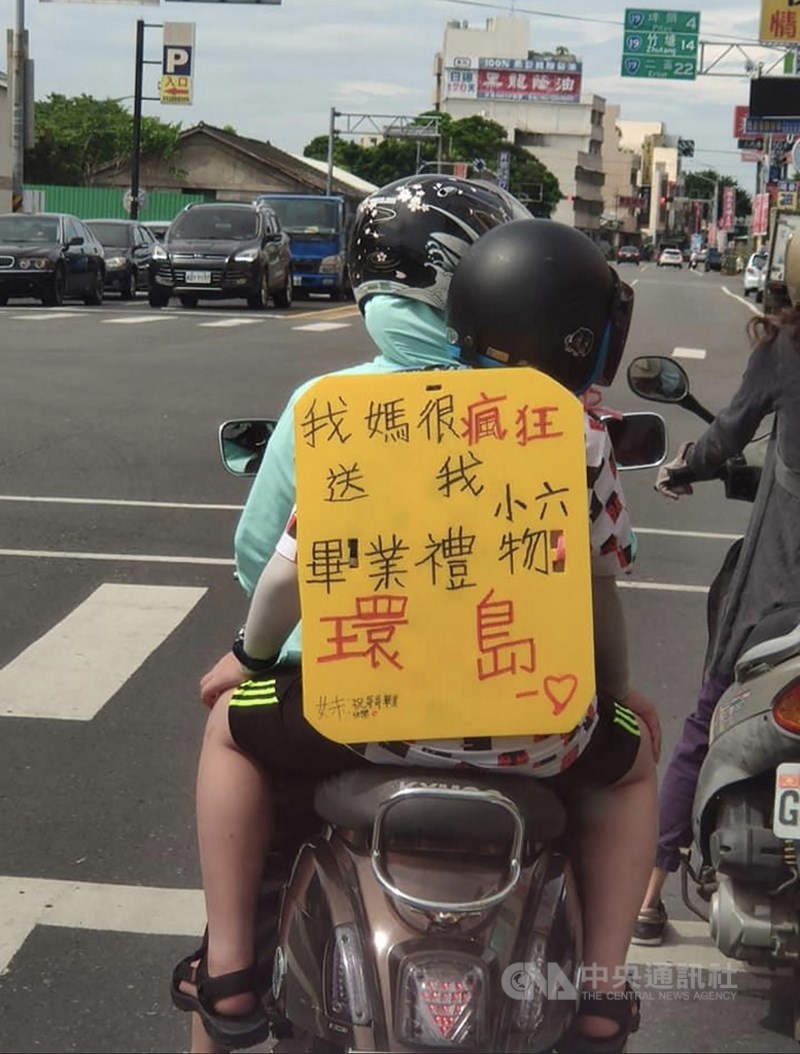 文史工作者蔣敏全在社群網站發文表示,他開車行經彰化溪湖鎮停等紅綠燈時,看到有一輛摩托車,媽媽載著孩子,孩子身上背著黃色字牌,寫著:「我媽很瘋狂送我小六畢業禮物(環島)」。(翻攝照片)中央社記者吳哲豪傳真 109年7月8日