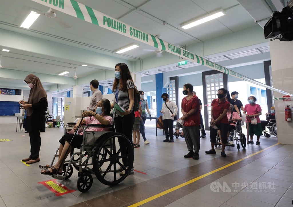 新加坡10日在疫情下舉行國會大選,選民保持社交安全距離,依序排隊進入德能中學投票站投票。中央社記者黃自強新加坡攝 109年7月10日