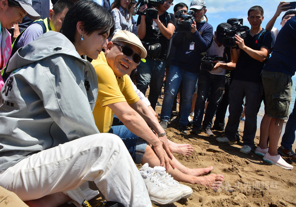 行政院長蘇貞昌(前左2)11日在民進黨立委賴品妤(前左1)等人陪同下,到新北市金山中角灣出席2020北觀山海樂活節衝浪活動開幕,在沙灘觀賞選手示範衝浪。中央社記者黃旭昇新北攝 109年7月11日