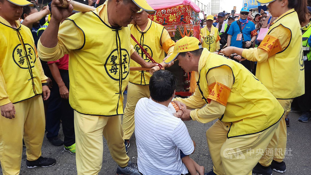 苗栗通霄拱天宮白沙屯媽祖回鑾,11日來到台中市,經過沙鹿區鹿寮成衣商圈時,一名服飾業者抱著生病的孫子跪在神轎前,求媽祖保佑孫子能平安長大。(民眾提供)中央社記者蘇木春傳真 109年7月11日