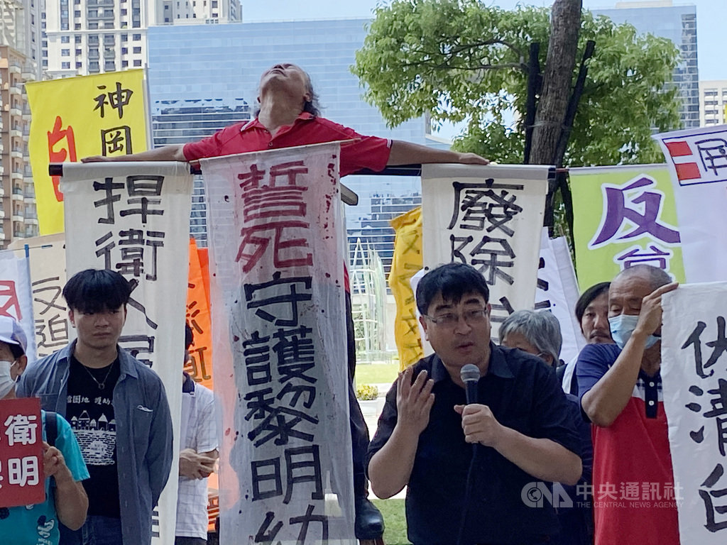 台中黎明自辦重劃會向法院聲請執行拆除黎明幼兒園,緩拆期限將在20日到期,幼兒園長林金連(後左2)13日將自己綁在十字架上,並貼上白布條,與公民團體召開記者會,他表示,針對幼兒園迫遷問題,他曾經在台中市長盧秀燕上任前,要求解決重劃會諸多違法造成的不公問題,但市府卻持續神隱至今。中央社記者蘇木春攝 109年7月13日