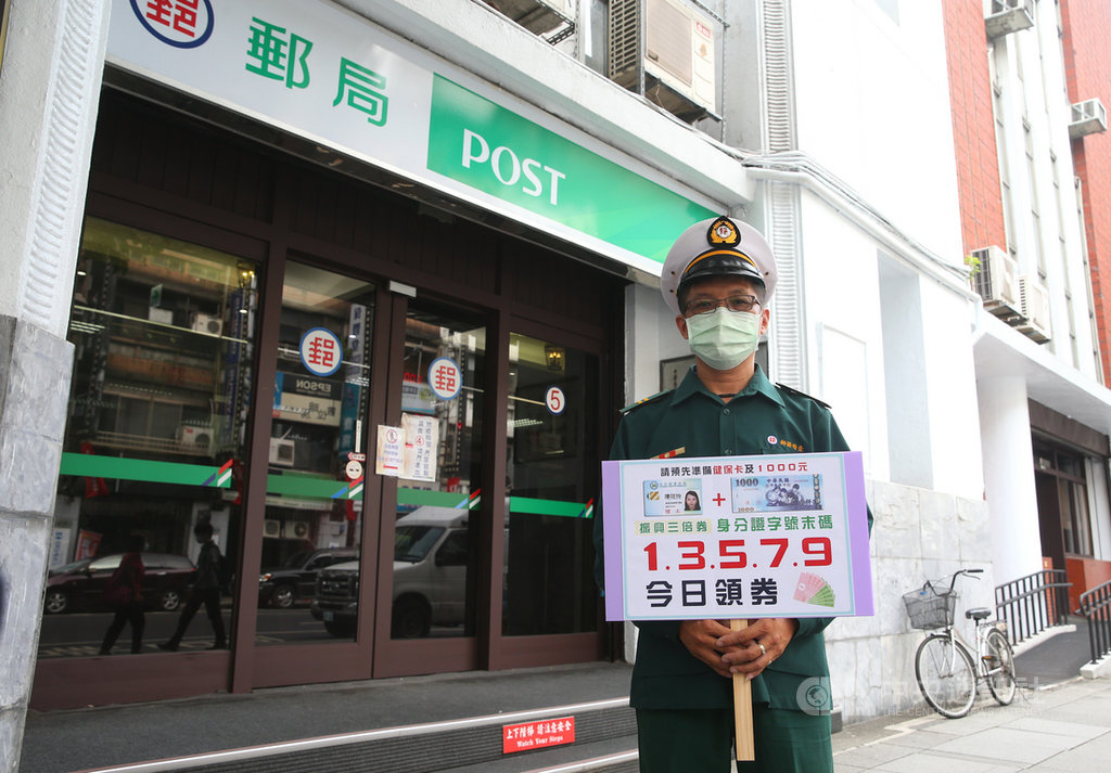 紙本振興三倍券15日開始在郵局購買領取,工作人員拿著看板提醒民眾領取三倍券的相關注意事項。中央社記者謝佳璋攝 109年7月15日