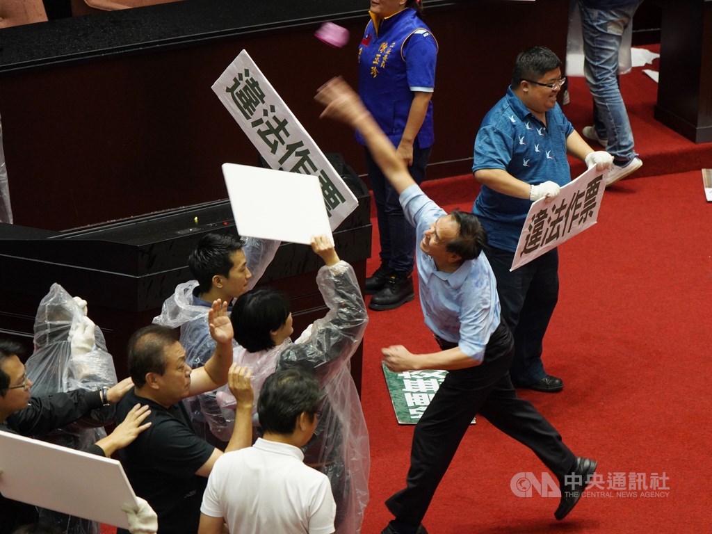 立法院會17日進行監察院人事同意權案投票,投票時間到中午12時截止,開票前,國民黨立委拿出預藏的水球,往主席台及票匭處猛丟,企圖阻止開票;民進黨立委則穿雨衣、以保麗龍板遮擋。中央社記者徐肇昌攝 109年7月17日