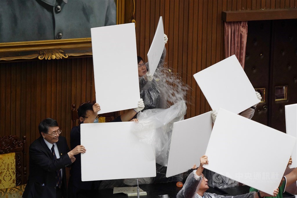 立法院會17日進行監察院人事同意權案投票,中午開票前,國民黨立委拿出預藏的水球,往主席台及票匭處猛丟,企圖阻止開票進行;民進黨立委則穿上雨衣,以保麗龍板保護立法院長游錫堃。中央社記者徐肇昌攝 109年7月17日