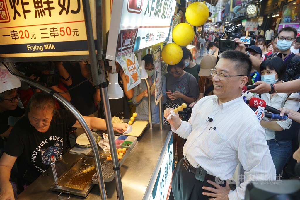 內政部長徐國勇(前右)18日晚間前往台北市士林夜市商圈,實地使用振興三倍券支持商家,沿途享用多種夜市小吃美食。中央社記者徐肇昌攝 109年7月18日