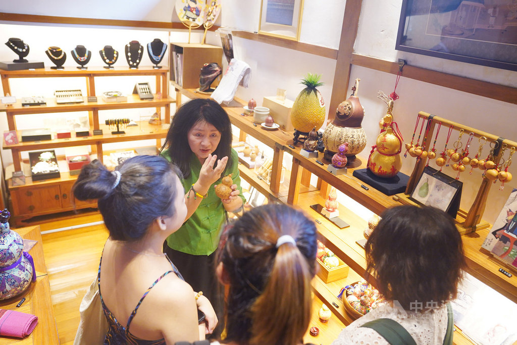 北投文物館藏身北投幽雅路,館長李莎莉(後)在館內禮品販賣區親自向遊客說明精美藝術品意涵。中央社記者徐肇昌攝 109年8月8日