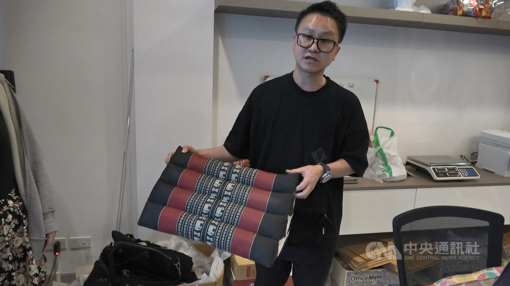 台灣人鄭鈞元在曼谷經營旅行社,因為武漢肺炎疫情影響,業績受重創,公司決定改做代購。圖為鄭鈞元手拿著台灣人喜愛的泰國紀念品三角枕。中央社記者呂欣憓曼谷攝 109年8月8日