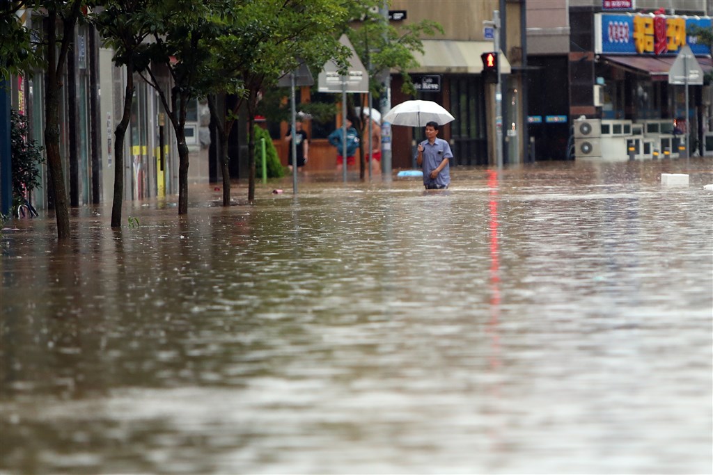 韓國氣象廳預估續有強降雨,濟州以外所有一級行政區土石流警報都轉為最高等級。圖為韓國光州道路淹水民眾涉水行走。(韓聯社)