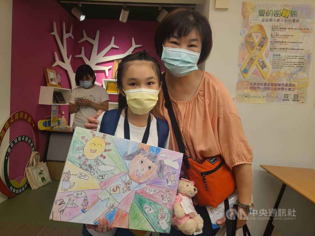 今年10歲的純純(左)曾罹患眼癌「視網膜母細胞瘤」,小小身軀歷經6次全身化療及各種大大小小的治療才成功抗癌,她12日拿著畫作,開心介紹畫上是化身超人的自己,希望未來能成為獸醫,救治更多動物。中央社記者張茗喧攝 109年8月12日
