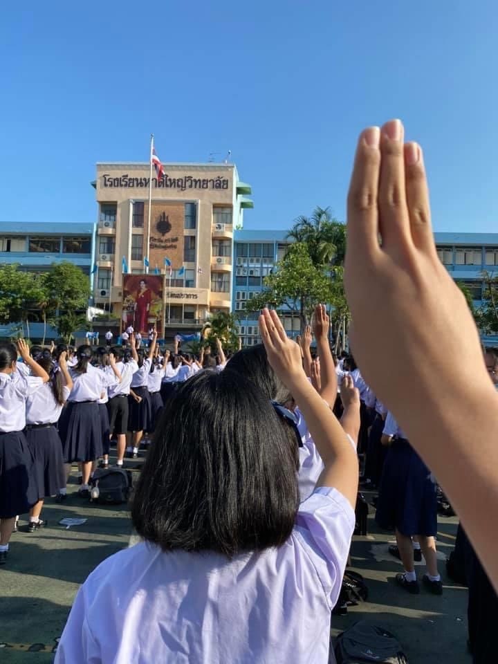 泰國近一個月以來的反政府示威抗議浪潮吹進高中校園,不少高中生在升旗時高舉三根手指的抗議手勢。(圖取自twitter.com/tanawatofficial)