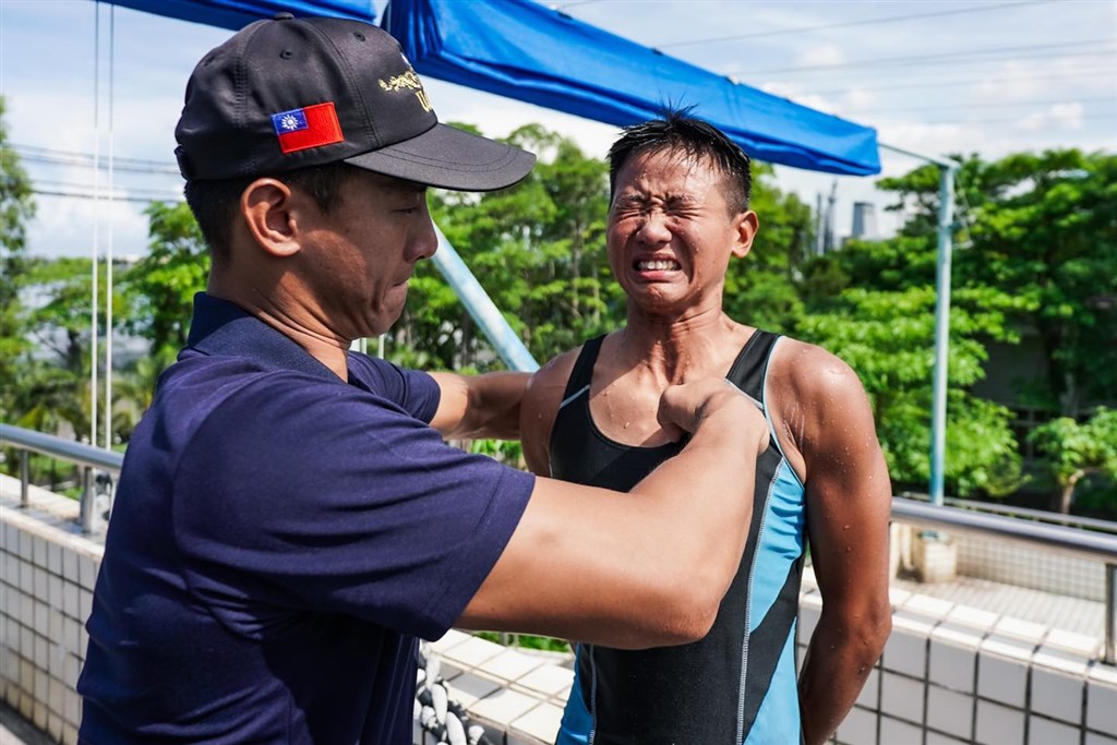海軍水下作業大隊新成員任婕(右)近日通過訓練,由已是隊員的哥哥任毅親釘象徵訓練合格的金龍徽。(圖取自facebook.com/ROCNAVY.tw)