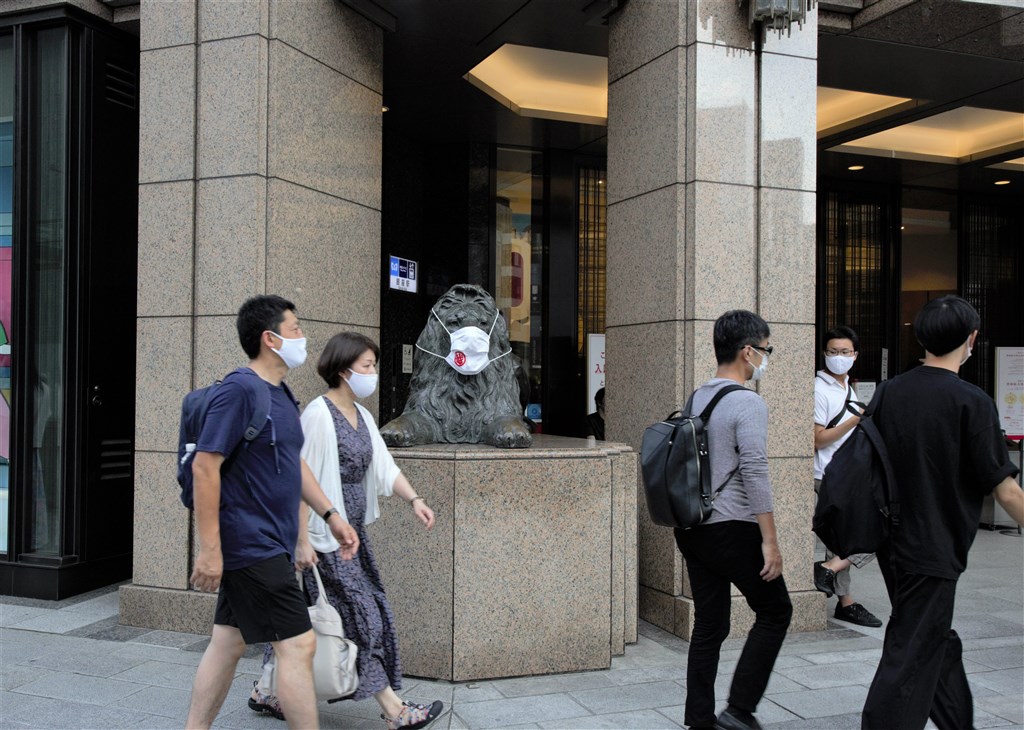 世界衛生組織秘書長譚德塞21日指出,全球對武漢肺炎大流行的掌控應能在2年之內達成,較遏止1918年流感大流行的速度快。圖為日本東京民眾戴口罩防疫,連店家門口的獅子雕塑也被戴上口罩。(中新社)