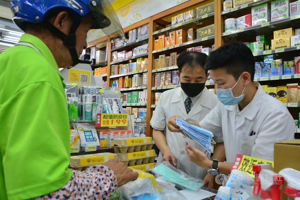 新莊區中港路美康健保藥局4日陸續有民眾湧入要更換加利公司口罩,洪姓男子(左)手持一大袋口罩,背包裡還有數包口罩,都是全家人的口罩要更換,藥師細心說明。中央社記者黃旭昇新北攝 109年9月4日