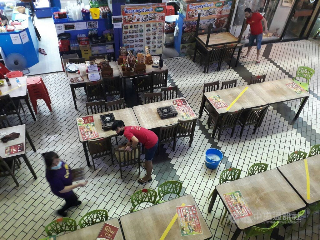 新加坡防疫武漢肺炎結束阻斷措施進入鬆綁過渡期,經濟發展與旅遊業疲弱不振。圖為新加坡小泰國區餐飲業者擦拭桌椅消毒。(中央社檔案照片)