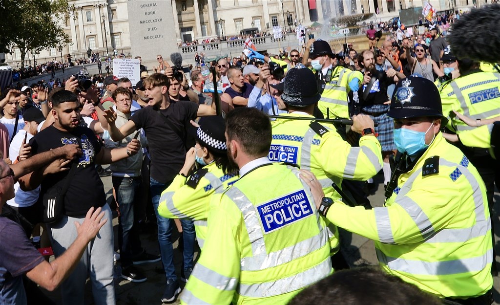 為因應武漢肺炎病例激增,英國19日宣布嚴格新規定,民眾如果拒絕自我隔離以遏止病毒擴散,最高可處1萬英鎊(約新台幣38.7萬元)重罰。圖為倫敦民眾抗疫防疫措施與警方對峙。(安納杜魯新聞社)