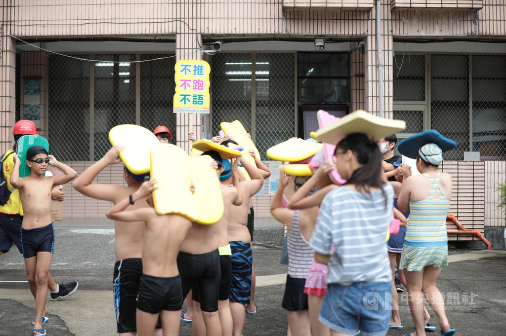基隆市碇內國小21日舉辦地震避難演練,其中一項假定在泳池上課時遇到警報應變,師生立即迅速上岸、蹲下靠牆,並以浮板保護頭部。(基隆市政府提供)中央社記者王朝鈺傳真 109年9月21日